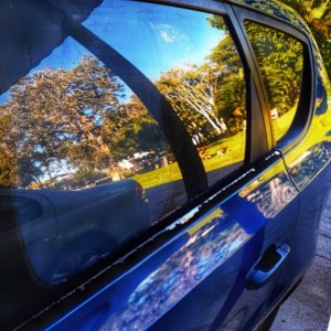 A blue car parked beside a park