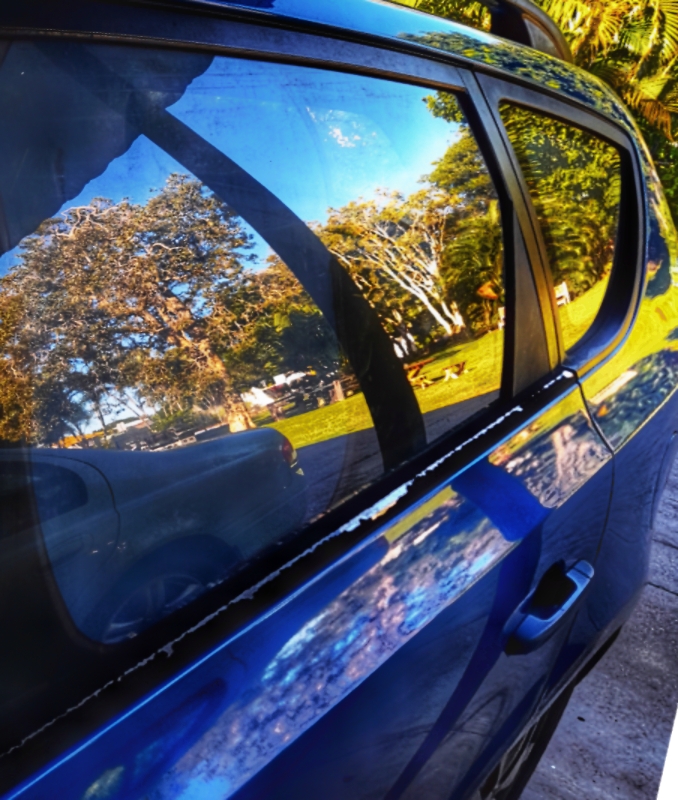 A blue car parked beside a park